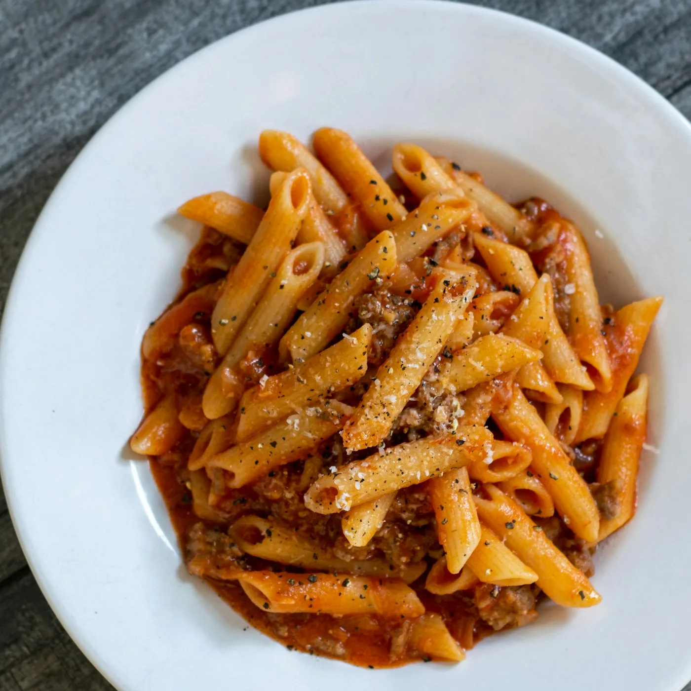 Frisch angerichtete Penne mit Tomaten-Ragù und Parmigiano