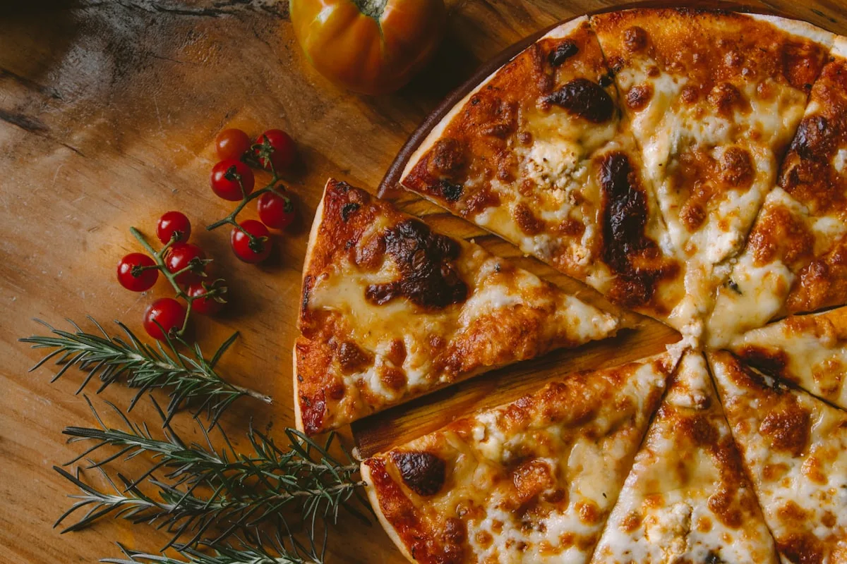 Frische Pizza aus dem Holzofen mit Rosmarin und Kirschtomaten